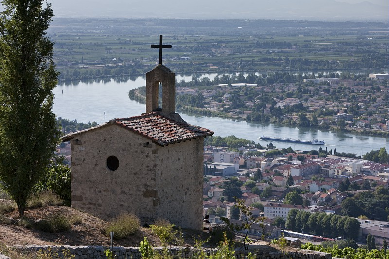 Downward view of the river and a river cruise ship, with a church and in the foreground.