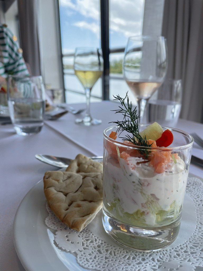 Salmon verrine and cream cheese, along with pieces of focaccia and a glasses of wine, at the restaurant table on the MS Camargue cruise ship.
