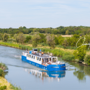 MS Anne-Marie canal barge cruising along the Canal du Rhône near Sète under blue skies, surrounded by peaceful waterways and lush landscapes.