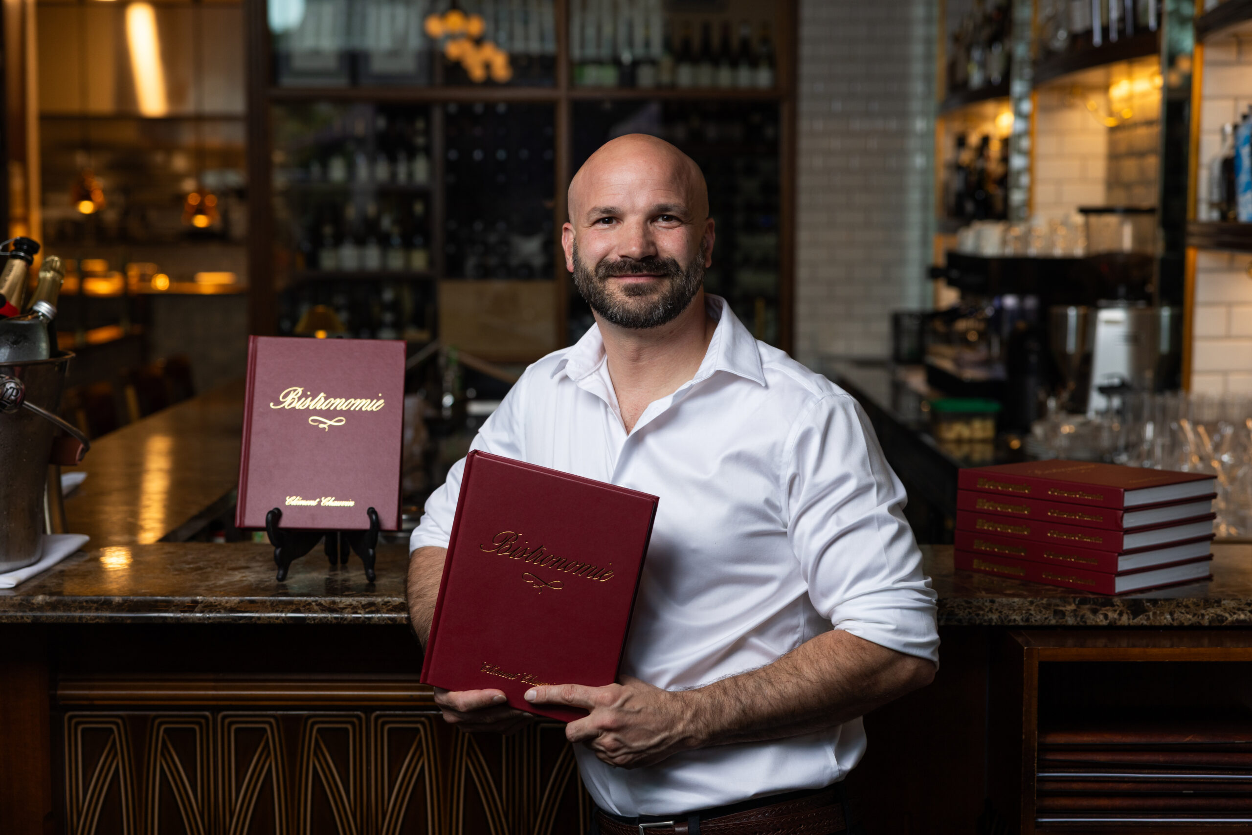 Michelin-star trained Chef Clément Chauvin at Restaurant Montrachet holding his award-winning cookbook Bistronomie.